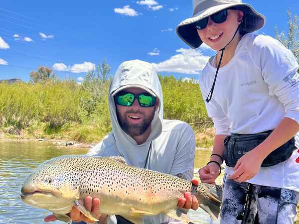 Father and son fly fishing with brown trout