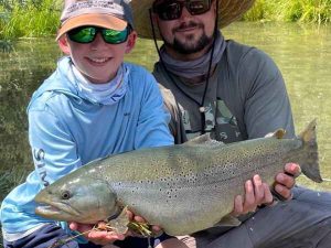 Fly guide and young boy fly fishing brown trout