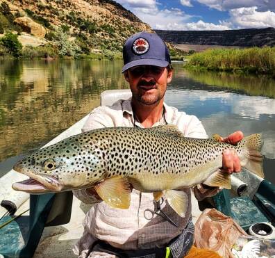 Guide holding large brown trout san juan river