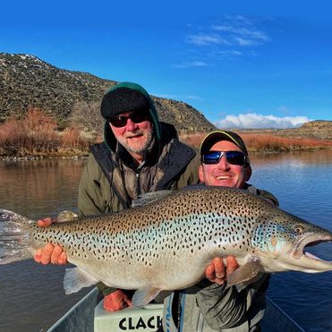 Two men on san juan river winter holding large trout